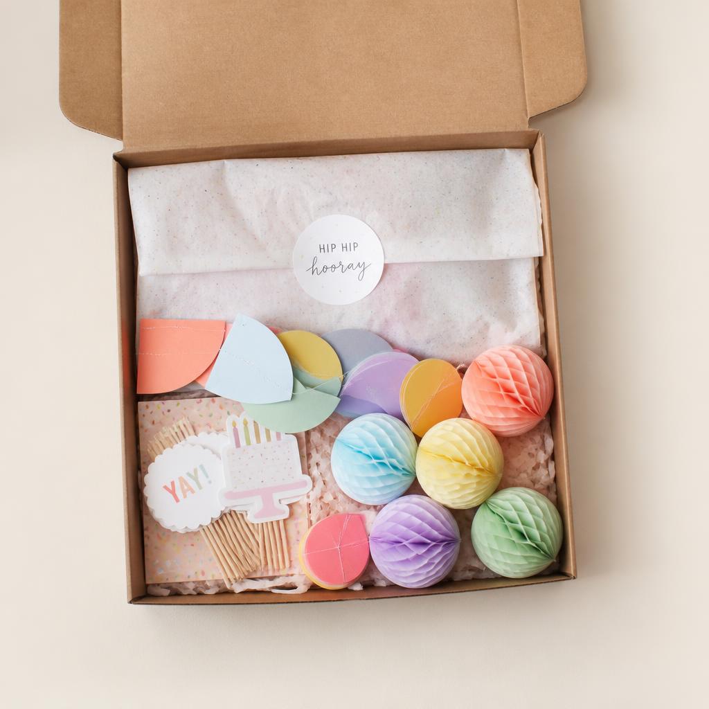 Caja de confetti abierta con decoración de fiesta en tonos pastel